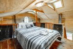 queen bed in loft space above the living area